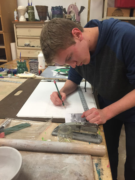 Junior Garrett Smith works on a drawing of his house for his drawing and painting class.