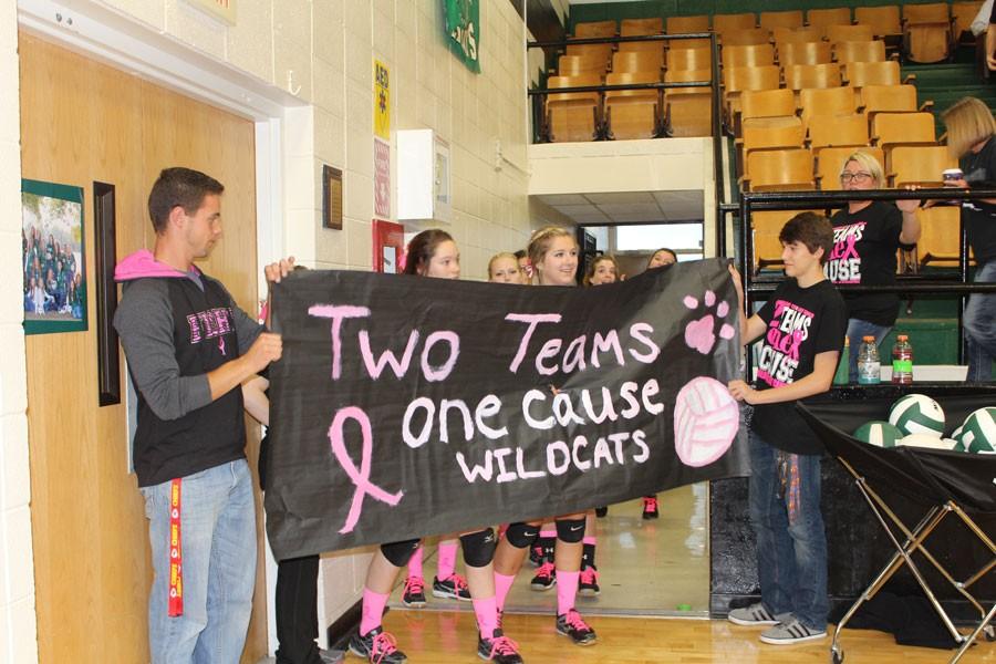 Senior John Hargrave and junior Tommy Reffett hold a banner that was made for the varsity volleyball team to run through. The team played their Pink-Out game against Southern Boone and lost in two sets. 