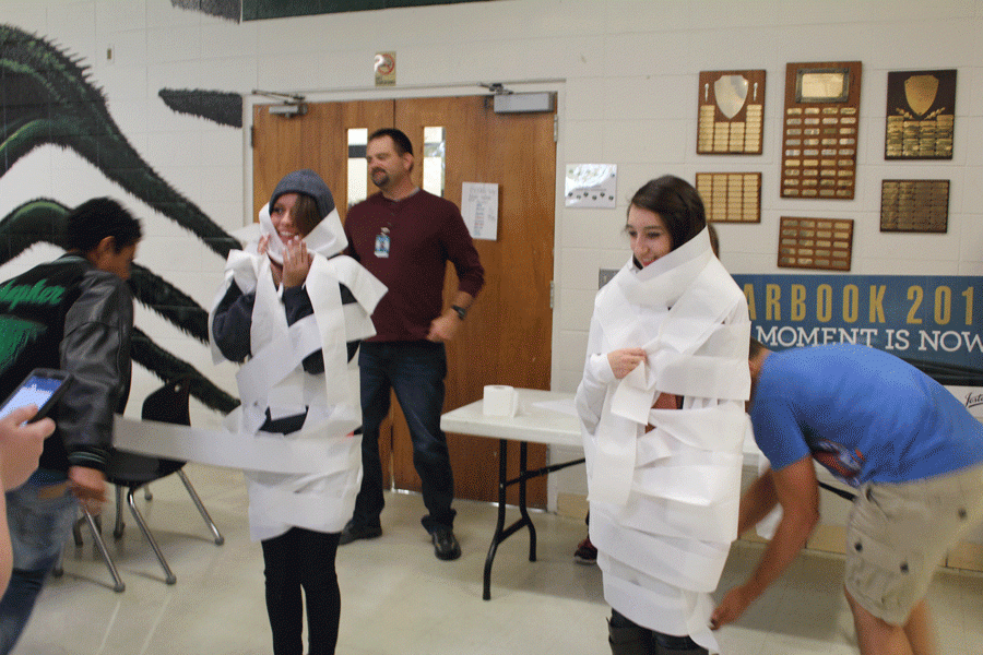 Senior Austin Steenburgen  and  sophomore Jayden Schepker mummify  junior Mericia Wilbanks and sophomore Kyra Kleihauer in the cafeteria. They were doing this to promote yearbook purchases and the best mummy got a candy bar.