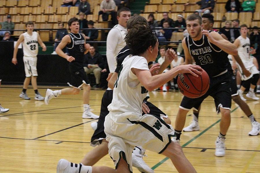 Freshman Logan Davis dribbles the ball down to set up a play during a game against Skyline. Davis started varsity this year. 