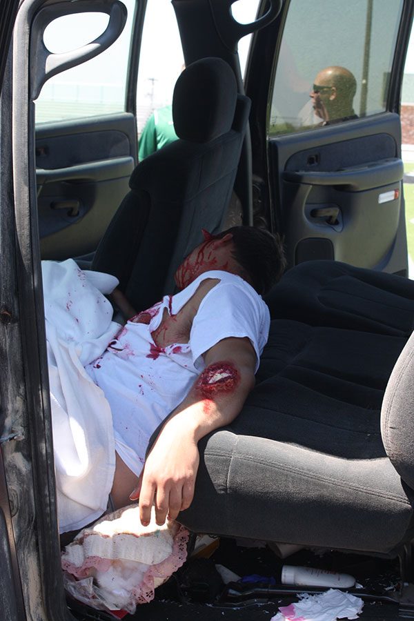 Senior Austin McCall pretends to die in the staged car accident. McCall and other volunteer students were made to look gory with fake blood and prosthetic injuries. 