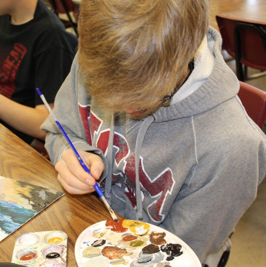 Senior Carter Phillips works on a painting in his art class.