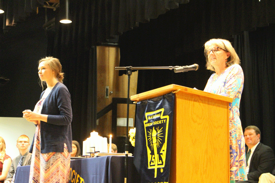 Junior Ashton Adams stands on stage while being inducted into NHS by Marsha Eaton. Eaton was Adams 3rd grade teacher. 
