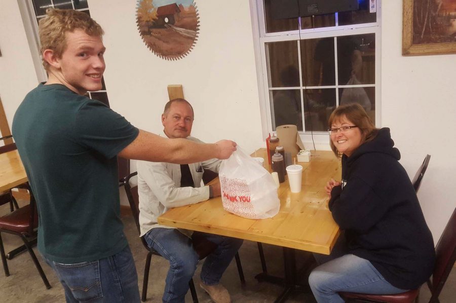 Senior Michael Pierce hands a to go order to regular customers, Wes and Tawnya Conner. Pierce  has worked at R&R Restaurant out in Tightwad since August.   