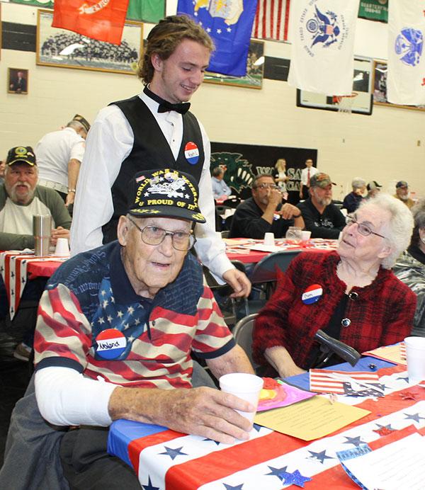Senior Student Council President Noah Long speaks to a pair of veterans during the veterans day breakfast. Student Council, NHS and FCCLA served veterans that day