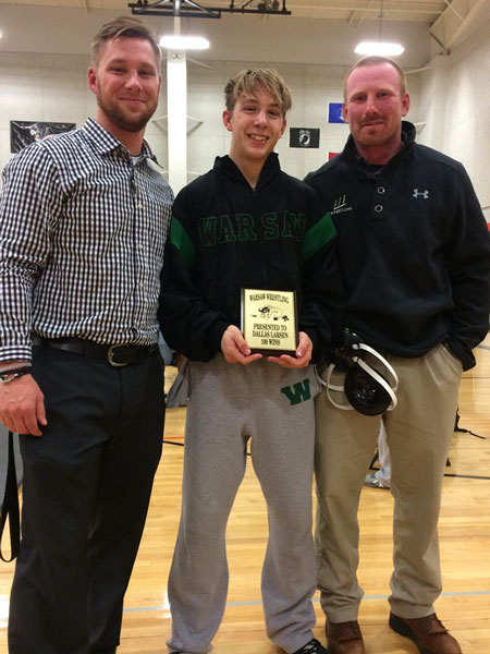 Coach Jared Steenburgen, junior Dallas Larsen and assistant coach Lance Estes celebrate Larsen’s 100th career win. Larsen achieved his 100th career win at the Dec. 6 meet against Versailles. 