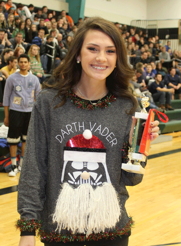 Madi Grobe holding up her trophy  for 1st place in the ugly sweater contest 