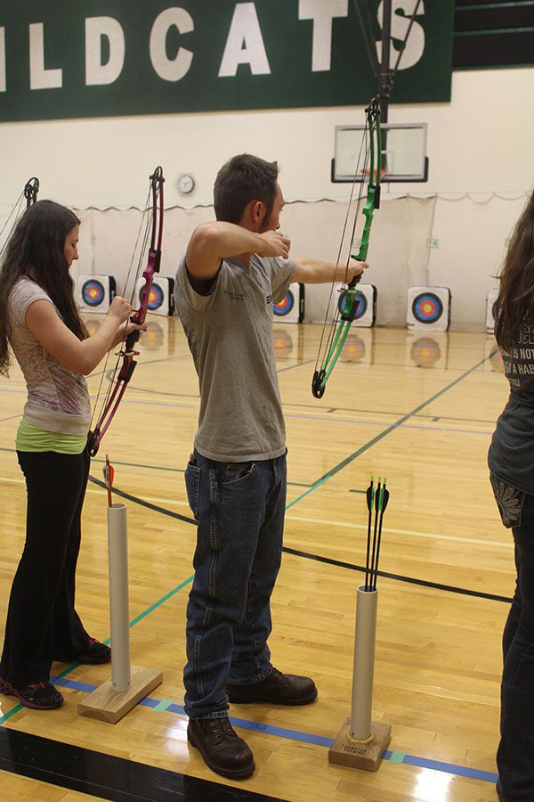 Junior Lee Newell prepares to shoot his bow as junior Kaylee Moody clips the arrow to the string. Newell has qualified for state archery for the second year. 