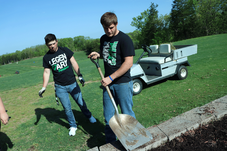 Seniors Dakota Bilderback and Corey Callahan shovel mulch at the Shawnee Bend Golf Course. This is the second year the school has organized a volunteer day for the graduating class to give back to the community.