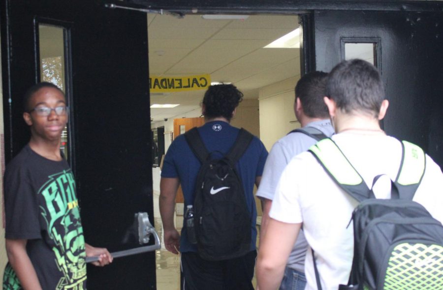 Freshman Ameer Evans holds the door open for students on their way to class. Evans makes this a recurrence everyday. 
