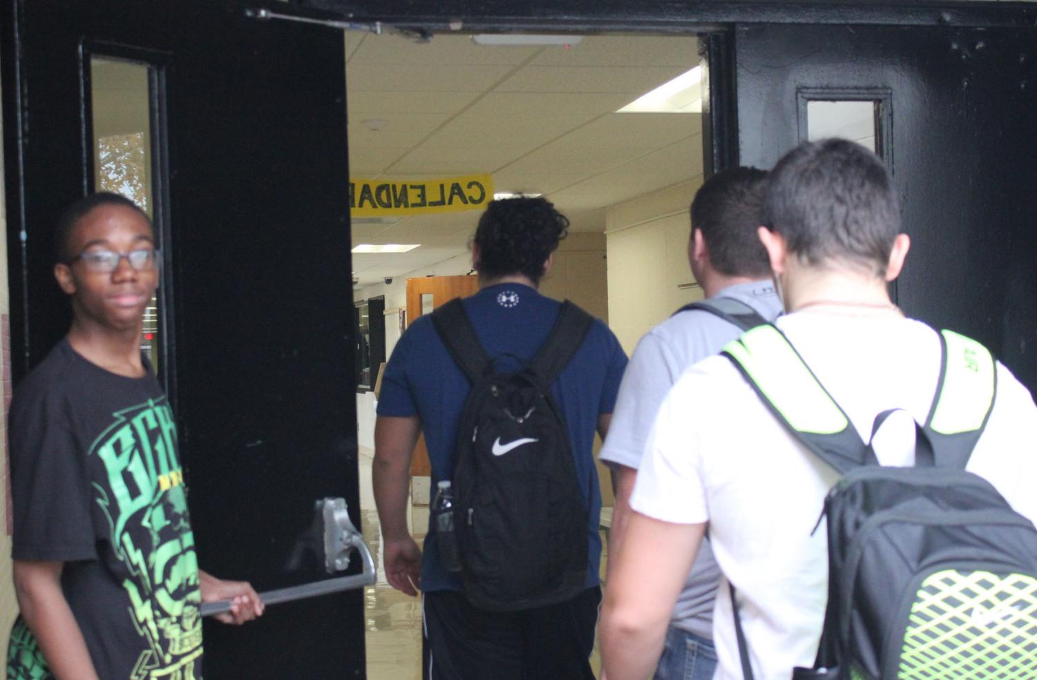 Freshman Ameer Evans holds the door open for students on their way to class. Evans makes this a recurrence everyday.