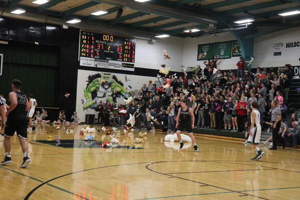 Students throw stuffed animals onto the court as the players walk off. Stuffed animals were given to Christmas for kids.