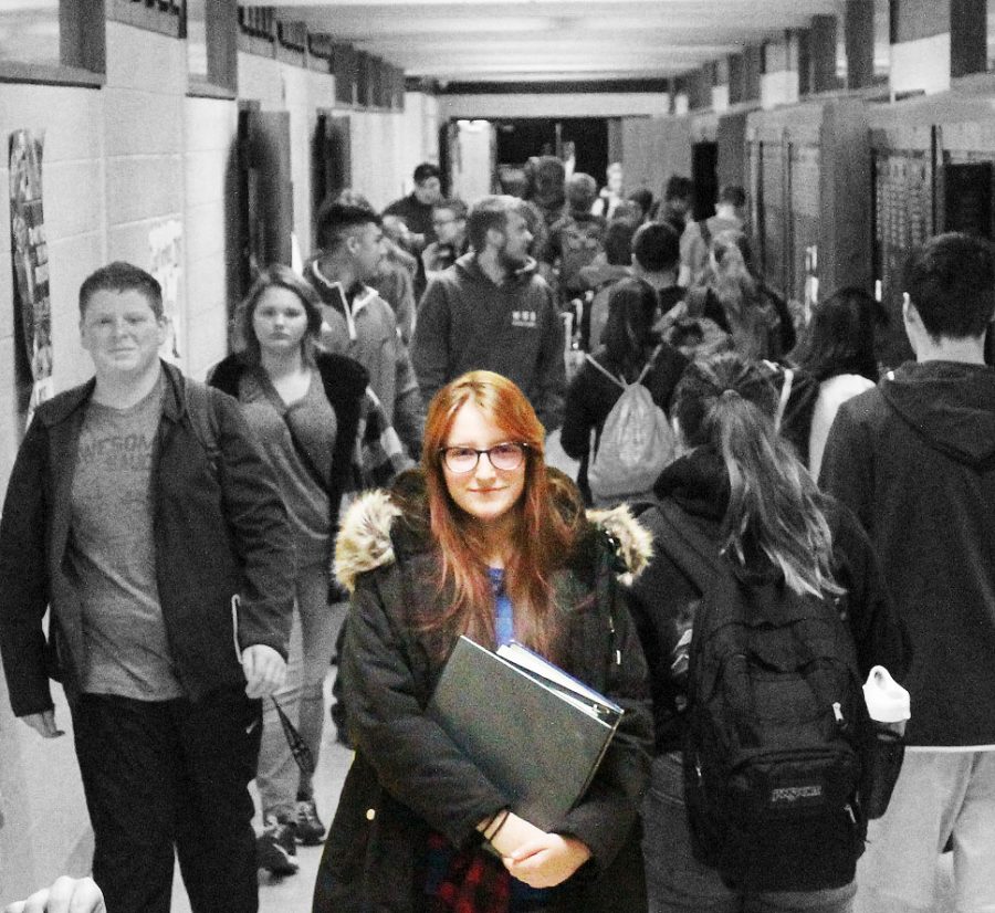 Sophomore Alexa Scrivener standing in hallway surrounded by fellow classmates 