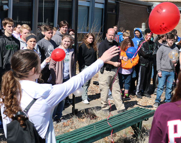 Senior Kyra Kleihauer releases one of the red balloons at the balloon release on March 14. Each red balloon had a name of a victim from the Parkland, Florida shooting.  