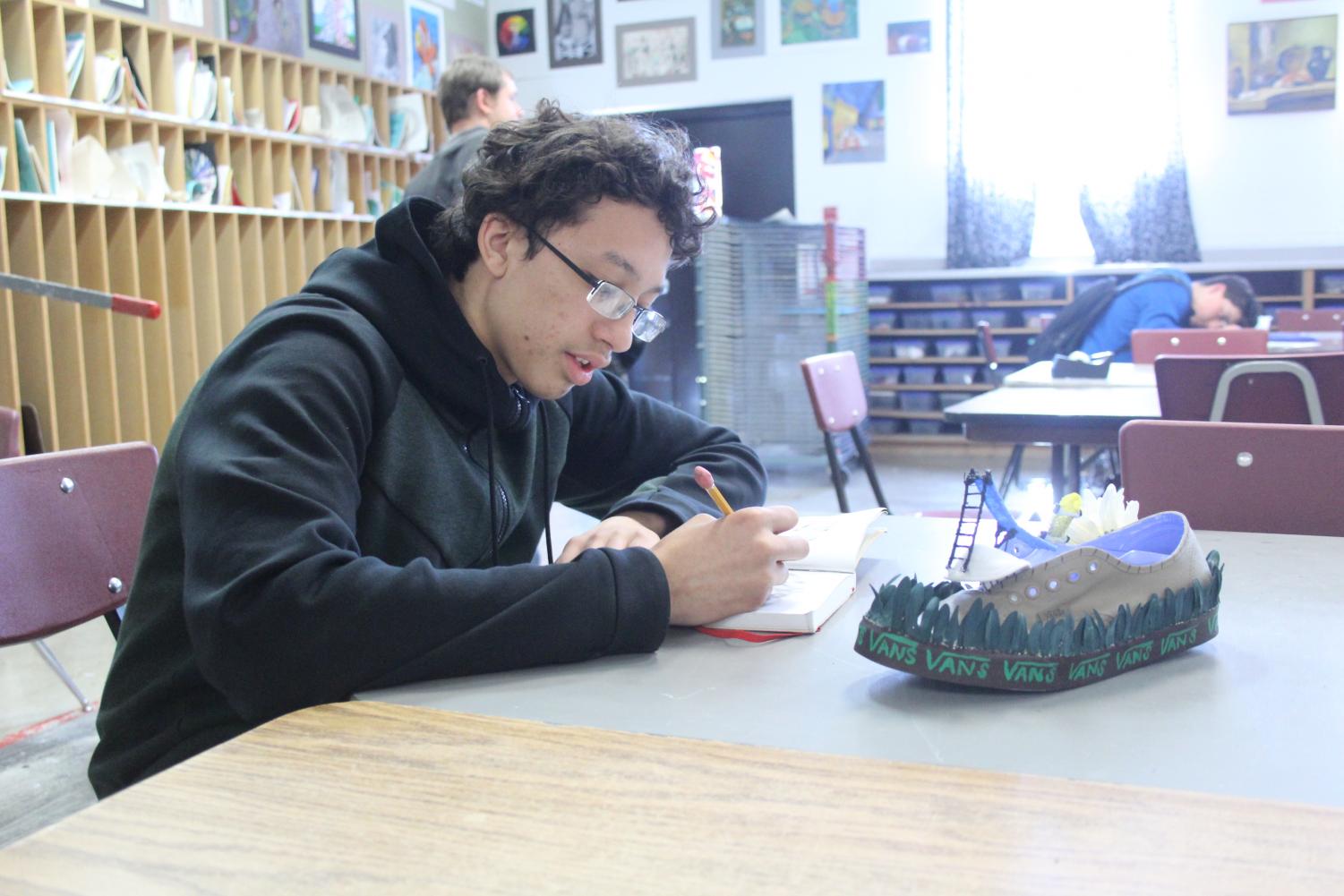 Junior Dayvon Bruce works on drawing ideas for a new assignment after completing his Vans off the Wall Project in Jennifer Greene’s drawing and painting class.
