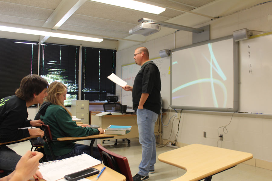 Kyle Stoecklein reviews the answers to a quiz in his 4th hour Geometry class. Junior Aidan Comer and Sophomore Brooke Spry make corrections.