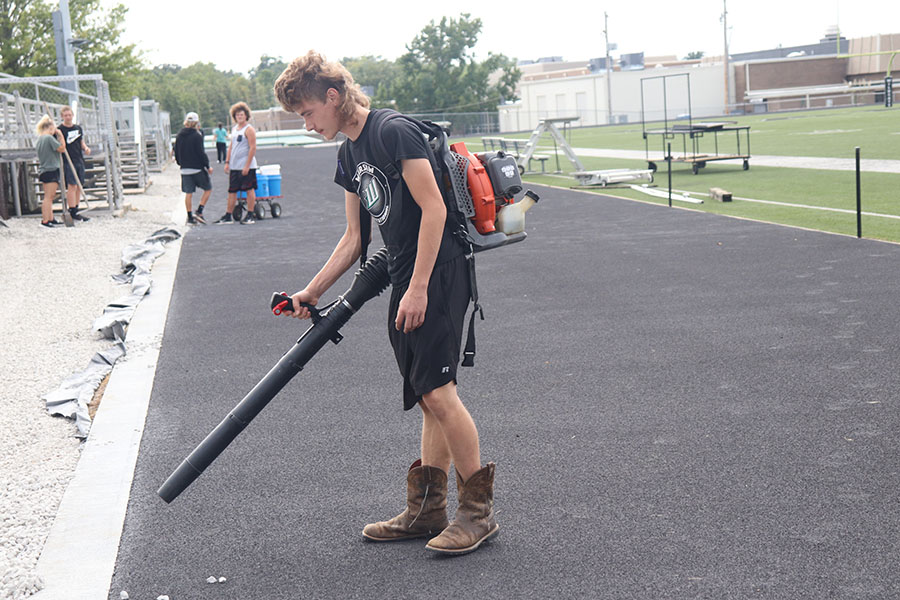 Sophomore Sean Owens uses a leaf blower to remove rocks from the newly surfaced track. PE classes helped prepare the track for paint.