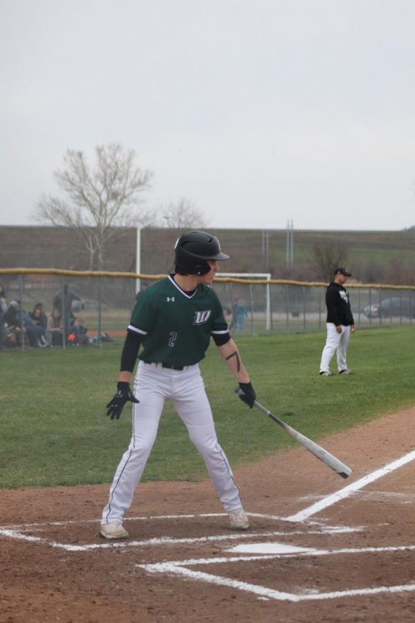 Senior Outfielder Bradley Brown stands at bat and prepares for a pitch from the Green Ridge Tigers during Warsaws senior night on March 22. Baseball players drew the number 7 on their arms to honor their late coach, Bailey Jelinek, who passed away on March 14.
