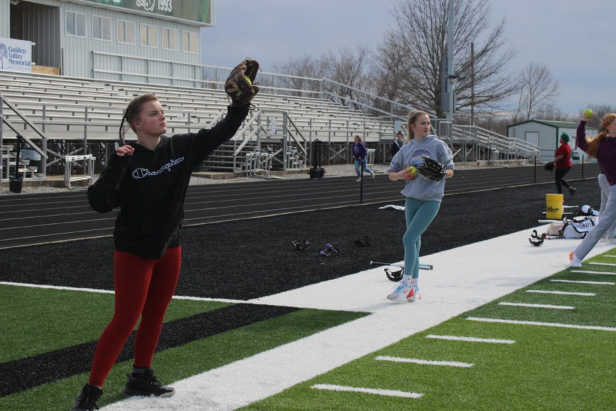 Freshman Hazel Thompson warms up playing catch at practice on the football field on March 25. The softball team beat Lincoln in their season opener on March 26.