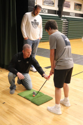 Freshman Carter Howell recieves help from principal Danny Morrison as coach Dennis Larson watches. Morrison individually helped many of the golfers. 