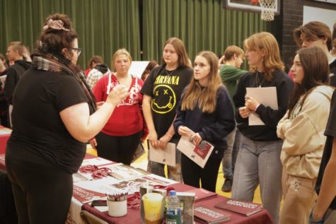 A group of students gets information from Evangel University at last month’s college fair. Some seniors have already received acceptances from colleges for next fall.