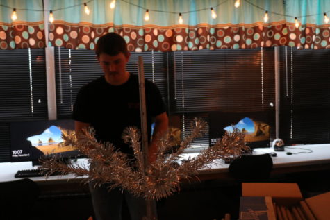 Senior Trevor Downing sets up business teacher Bethany Siegels classroom Christmas tree.