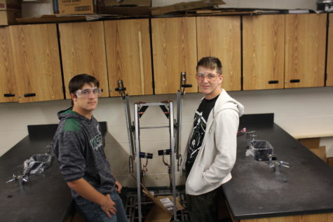 Junior Oliver Robertson and freshman J.C. Minks show off the robot they helped to build this fall. The robot could drive freely and climb monkey bars.