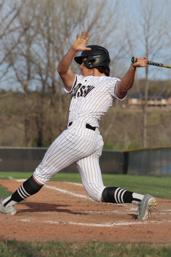 Left: Senior Tayten Boyer finishes his swing against Versailles. The Cats got the win 7-4 against the Tigers on April 6.
