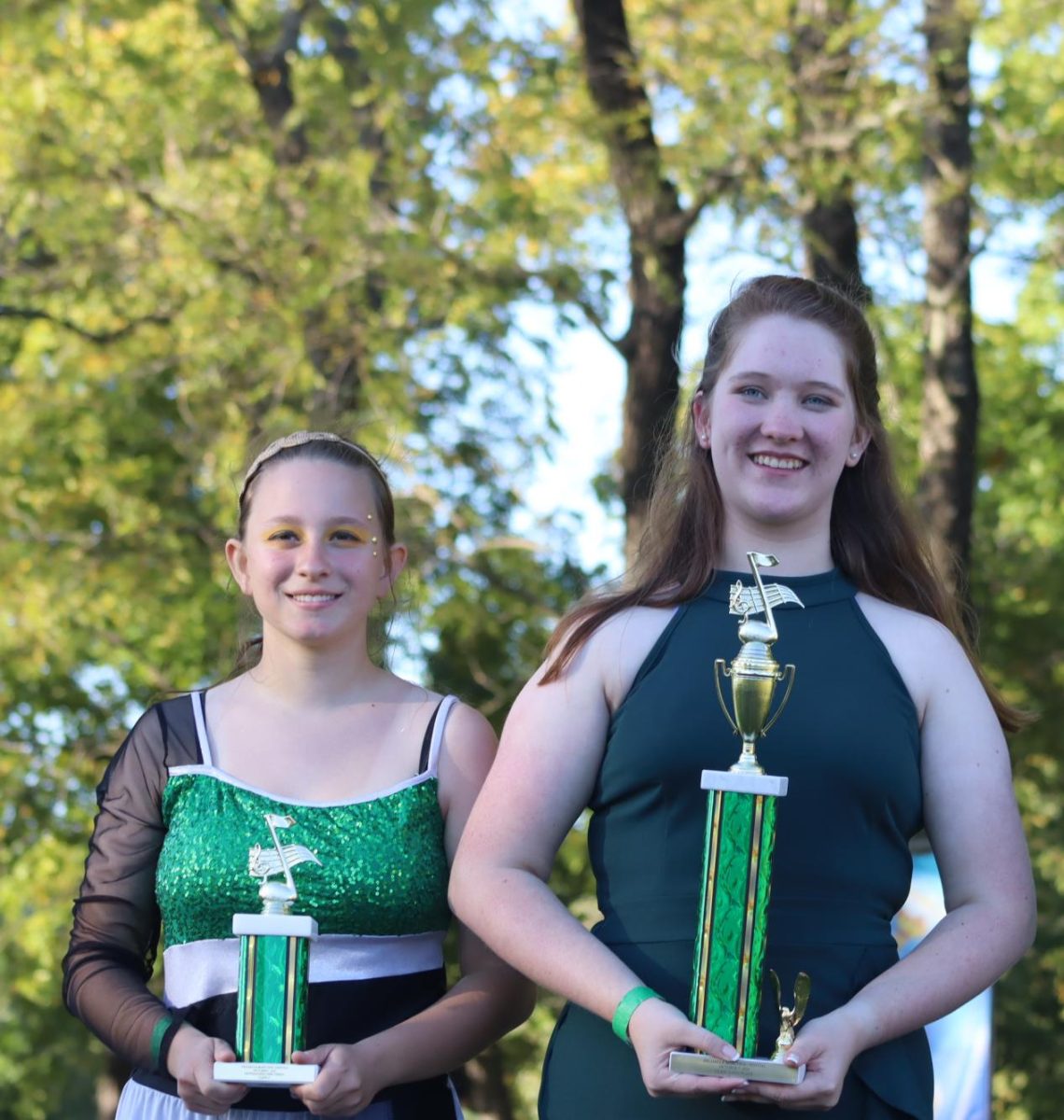 Drum Major Alyson Alcantara and Colorguard captain Marissa Ricke receive trophies at the marching band competition. The band received second place for their field show and outstanding percussion.