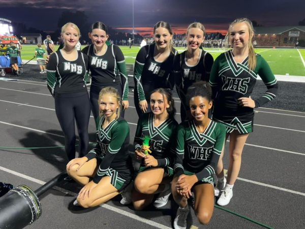 The Emerald Stars dancers take a break from their first sideline performance to participate in a team tradition of posing with “Emerald” the troll. They include: (front row) freshman Amelia Roberts, senior captain Tatum Bohl, freshman Addison Hill; (back row) Adele Anderson, junior Makayla Lawrence, senior Maddie Lawrence, freshman Macey Heimsoth and sophomore Bella Schwartz. 