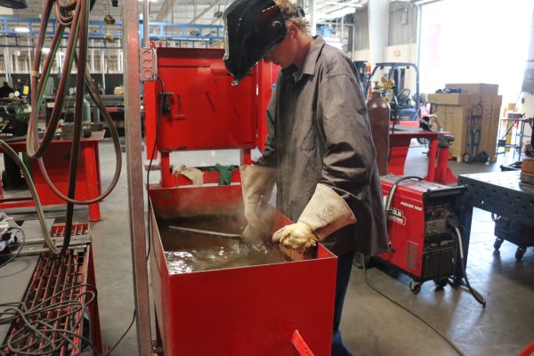 Junior Mason Gollihar cools  metal off in a dunk tank after welding on a building pad. 