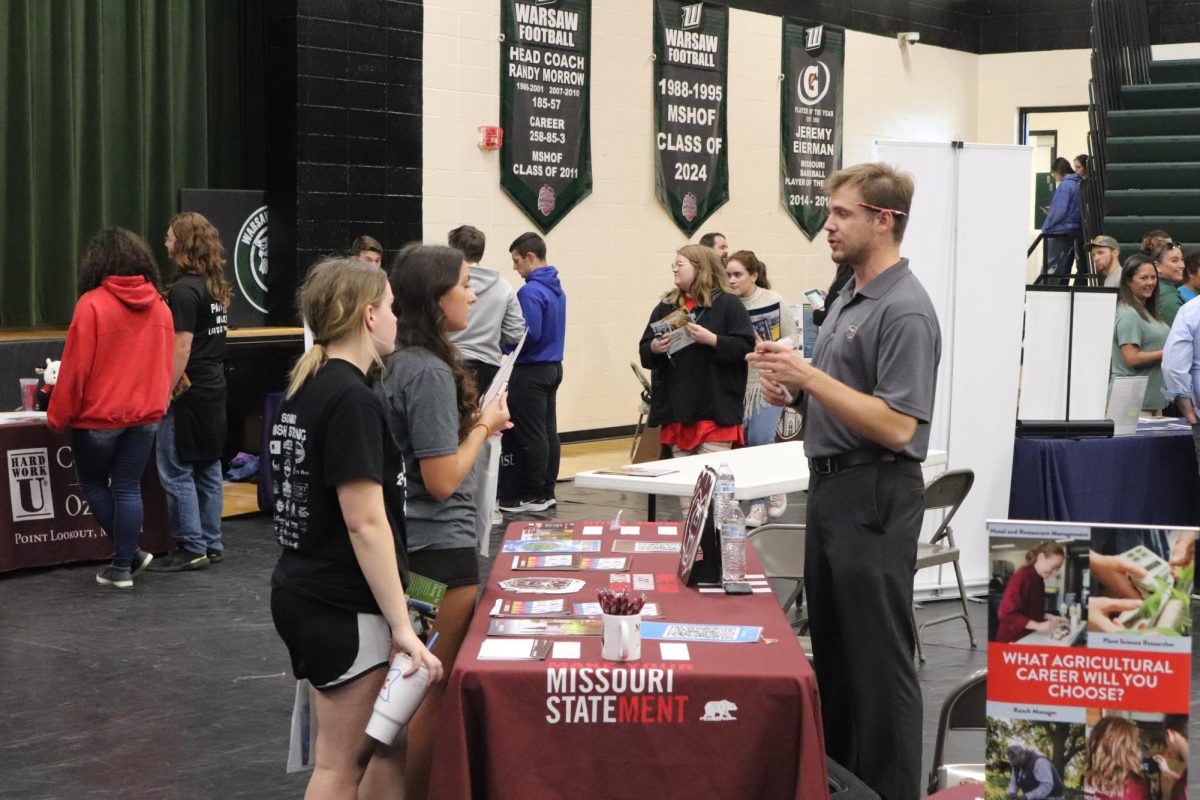 Seniors Hazel Thompson and Tatum Bohl talk with a representative from Missouri State University during the college fair on Oct. 18. 