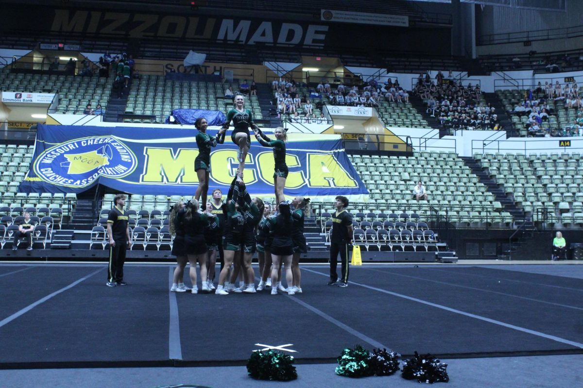 The WHS cheer team performs a pyramid with freshman Addison Hill, sophomore Izabella Schierholtz, and freshman Amelia Roberts in the air.