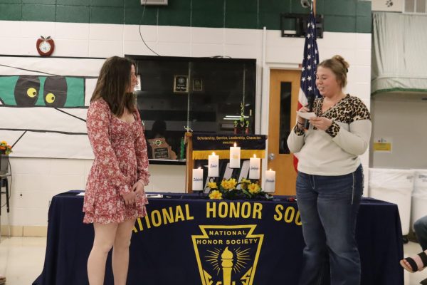 Junior Kimberly Tenold listens as senior Paige Collier inducts her into NHS. Each member read information about the new inductees during the ceremony.