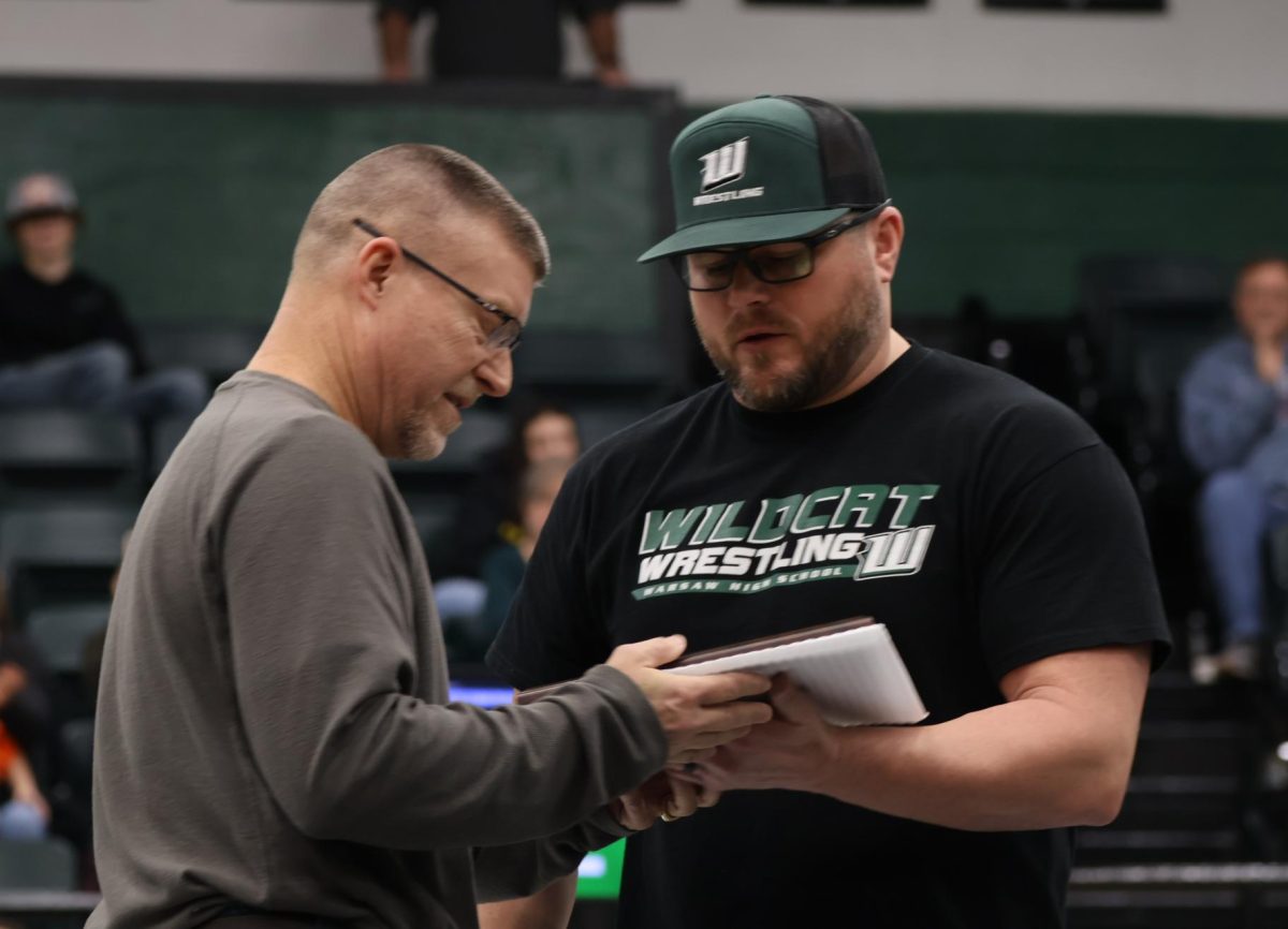 Wrestling head coach Justin Wisdom presents former wrestling coach John Duham with a plaque for the wrestling Hall of Honor on Jan 18. Duham was the first wrestling coach Warsaw had and he saw success with his coaching. 