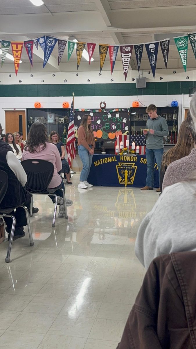 Junior Elizabeth Winters stands as senior Brennen Slavens reads about inducting her. Each member read information about the new inductees during the ceremony. 