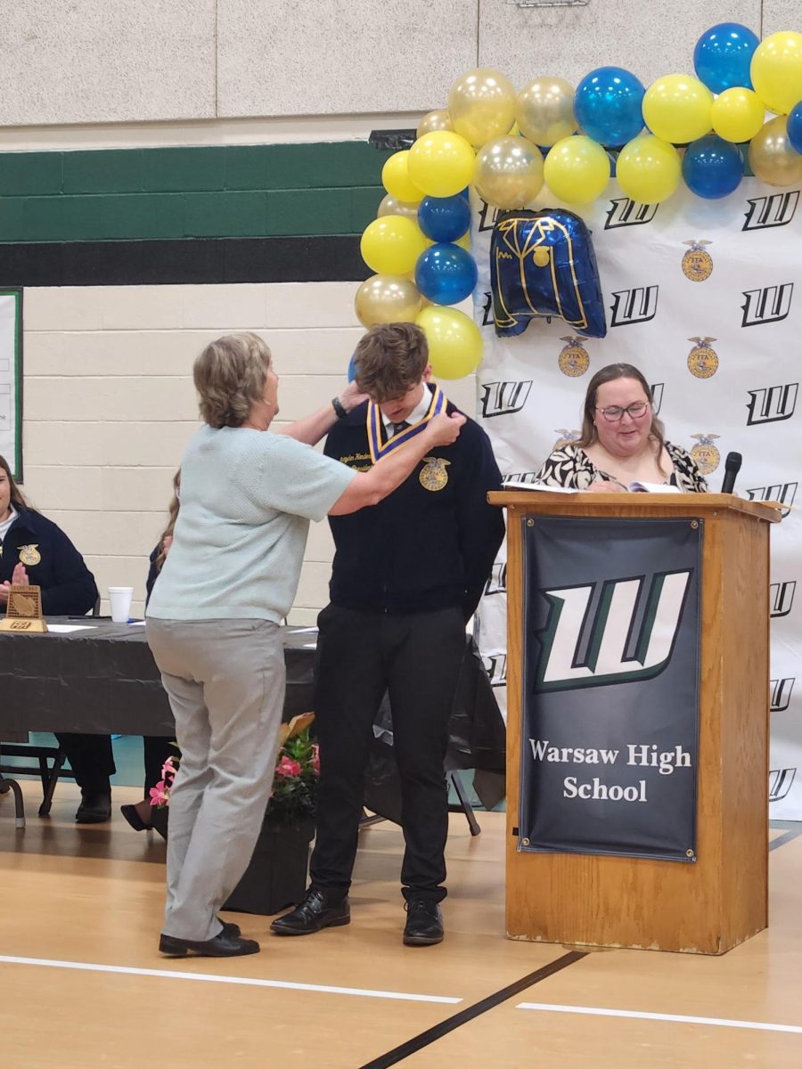Senior Brayden Henderson gets a medal laid on him from Downing at the FFA Banquet on May. 13. 